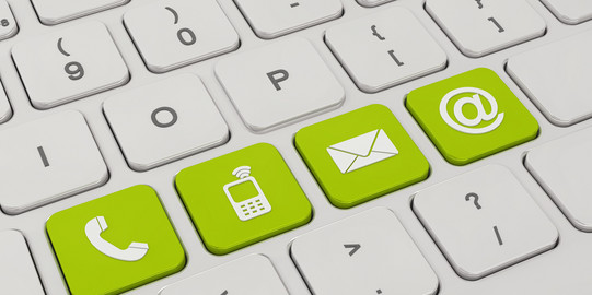 Auf einer weißen Tastatur sind vier Tasten grün eingefärbt. Darauf zu sehen sind Symbole für ein Telefon, ein Mobiltelefon, ein Briefumschlag und ein "at"-Zeichen.
